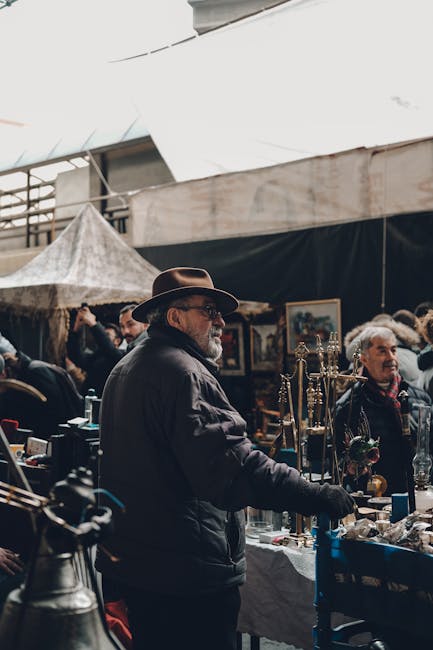 A jewelry trader working inside a market stall at Maltby Street Market in Bermondsey, focusing on the display of various rings, necklaces, and bracelets arranged neatly in open display trays on a coun