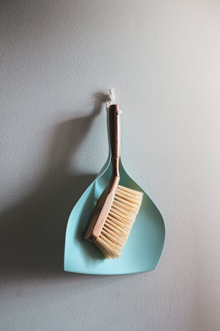 Three professional cleaners from Cleaners Bermondsey are conducting surface cleaning and deep cleaning tasks in a modern living room. The room features a large L-shaped sofa with fabric upholstery, po
